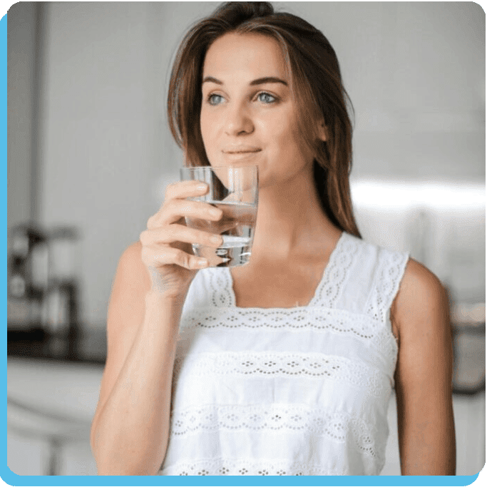 A woman holding a glass of water in her hand.